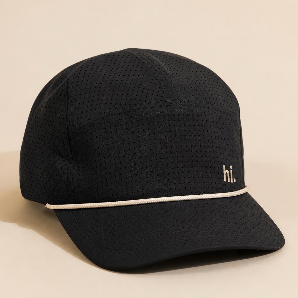 Performance Rope Hat — black with cream rope visor and a small cream 'hi.' embroidered on the front